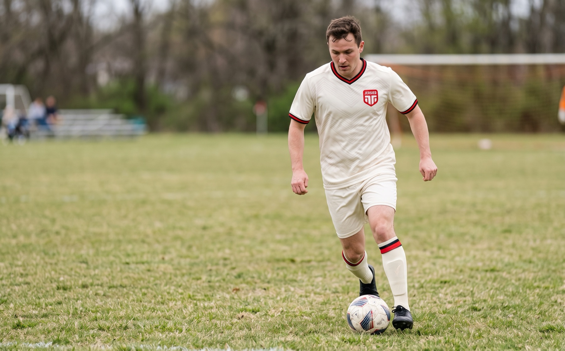 Soccer player dribbling the ball in a cream Jersied jersey