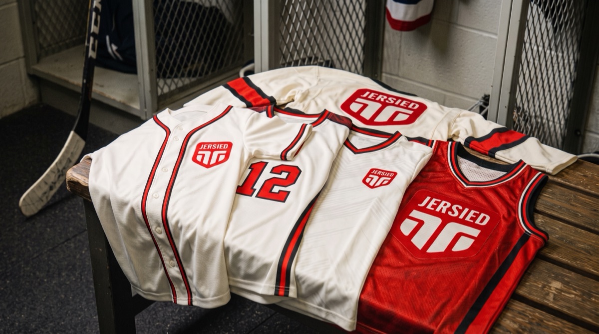 Jersied baseball, soccer, basketball and hockey jerseys laid out on a locker room bench